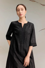 Close-up of a black silk A-line dress highlighting the V-neckline and exquisite floral bead embroidery, paired with a textured jacquard fabric, perfect for formal occasions.