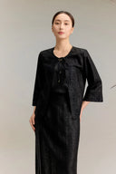 Full body shot of a black silk co-ord set featuring a three-quarter sleeve top with lace trim and tie-front detail, paired with a matching A-line skirt with lace hem, crafted from 100% mulberry silk.