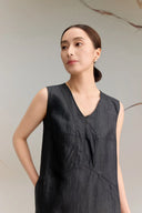 Close-up of a black silk V-neck dress highlighting the structural seam detailing below the bust, the textured jacquard finish of the fabric, and the elegant neckline.