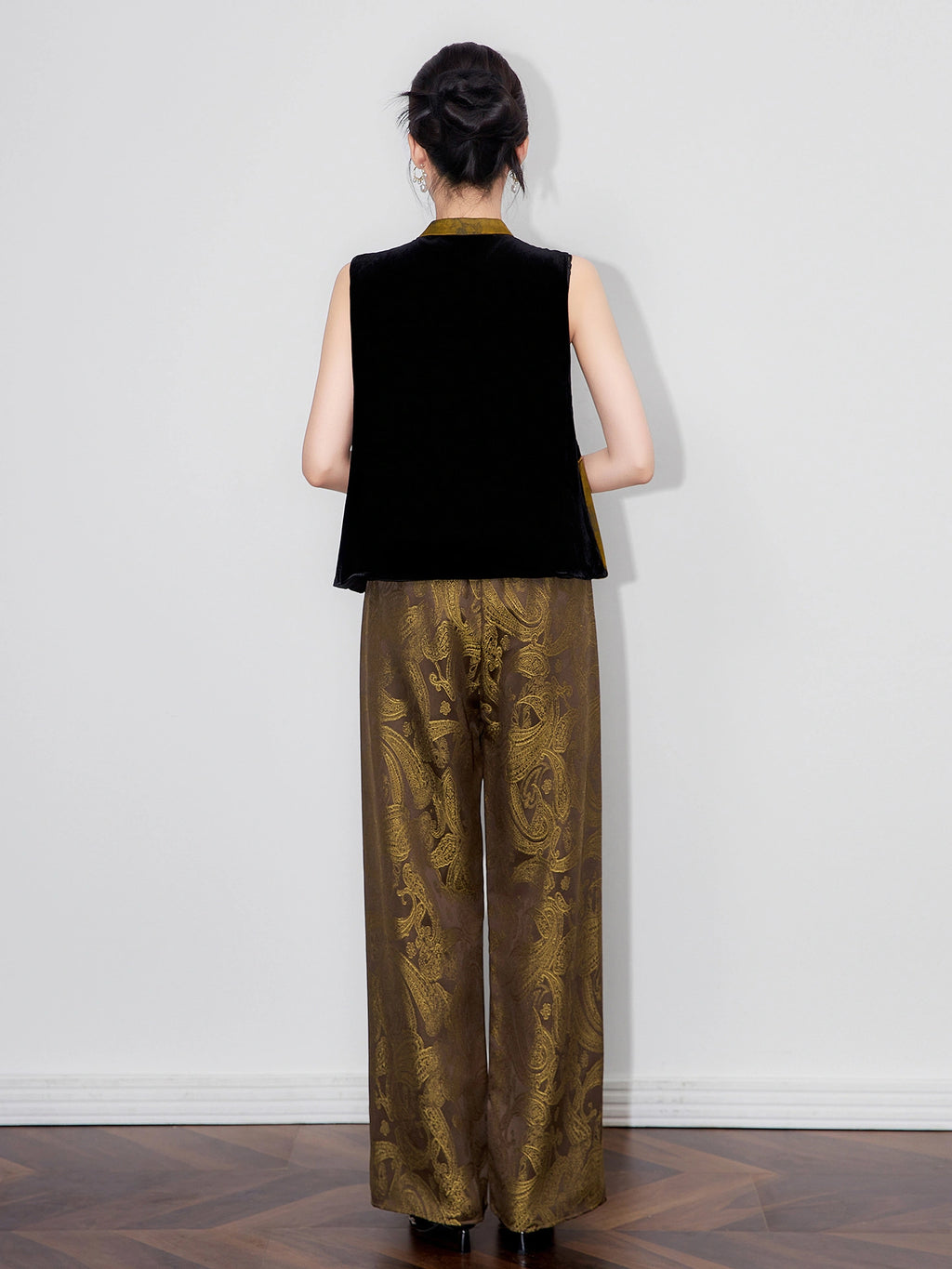 Back view of a model wearing a black sleeveless silk-base velvet Chinese-style vest.