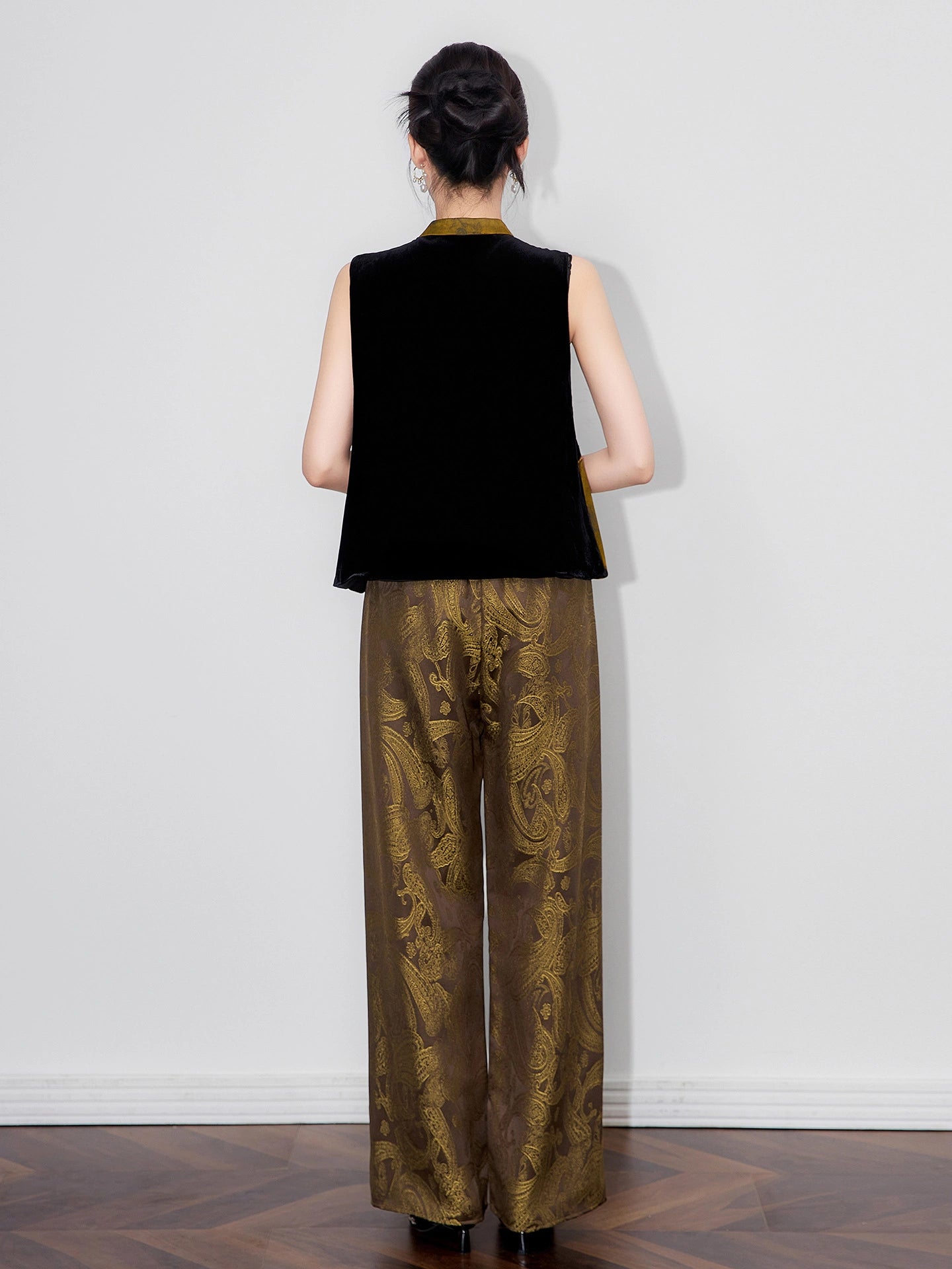 Back view of a model wearing a black sleeveless silk-base velvet Chinese-style vest.