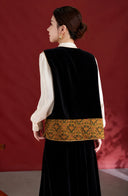 Back view of the black velvet vest with an antique gold and dark green patterned hem.
