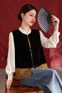 Seated model wearing the antique gold scroll-trimmed black velvet vest with an ivory blouse and jeans.