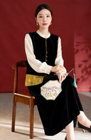 Seated model wearing the rabbit-patterned black velvet vest with an ivory blouse and a long black skirt.
