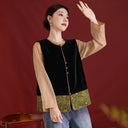 Angled view of the black velvet vest with a jade green floral hem, styled with a tan blouse.
