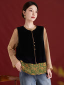 Black velvet vest with a jade green floral hem, worn over a tan blouse with jeans.