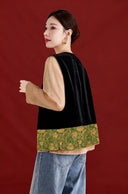 Back view of the black velvet vest with a jade green floral jacquard hem, worn with jeans.