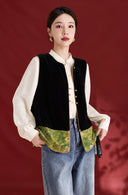 Model wearing the black velvet vest open, showing its green patterned hem over an ivory blouse and jeans.
