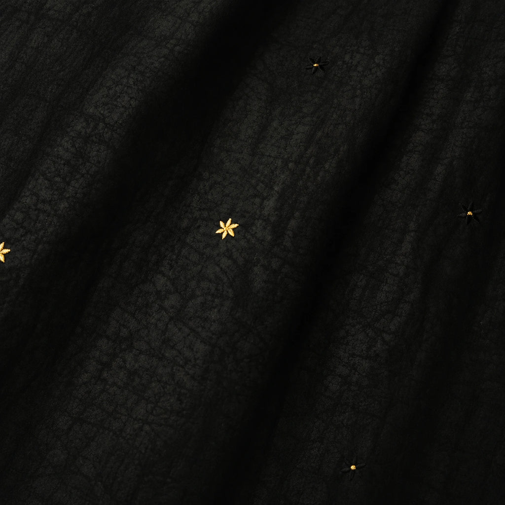 Close-up detail of black Xiangyunsha mulberry silk dress with delicate star embroidery texture