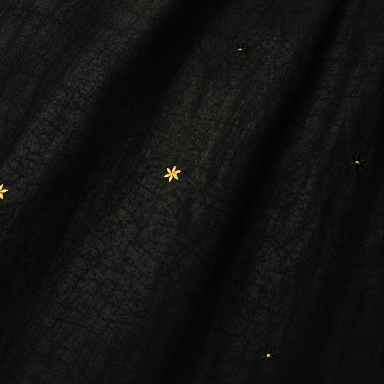 Close-up detail of black Xiangyunsha mulberry silk dress with delicate star embroidery texture