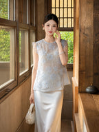 Front view of a light blue sleeveless top with 3D floral embroidery and shiny sequins, paired with a white satin skirt, 100% polyester.