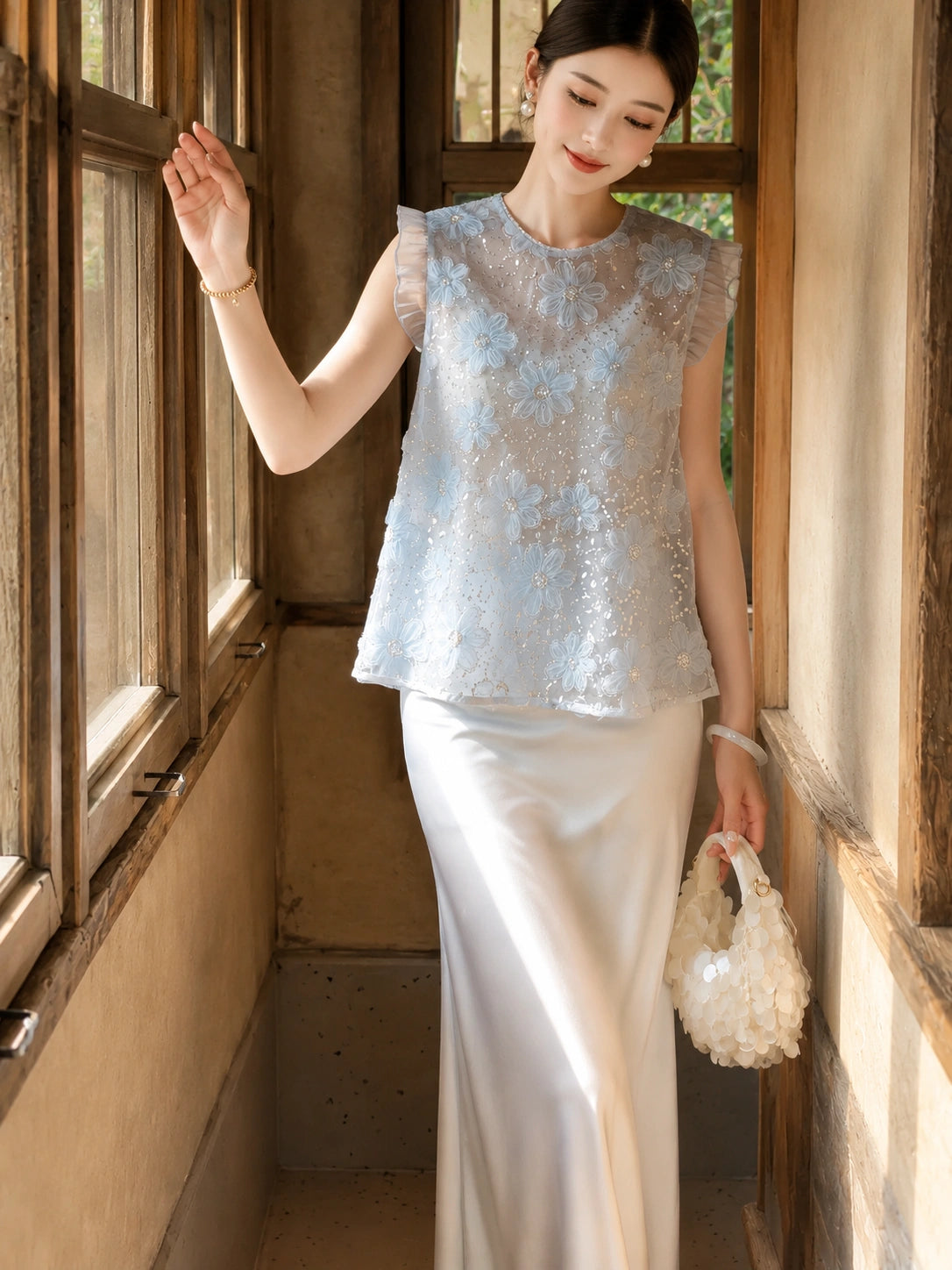 Side view of a light blue Cheongsam-style top featuring ruffle sleeves, floral details, and sequins, crafted from 100% polyester.