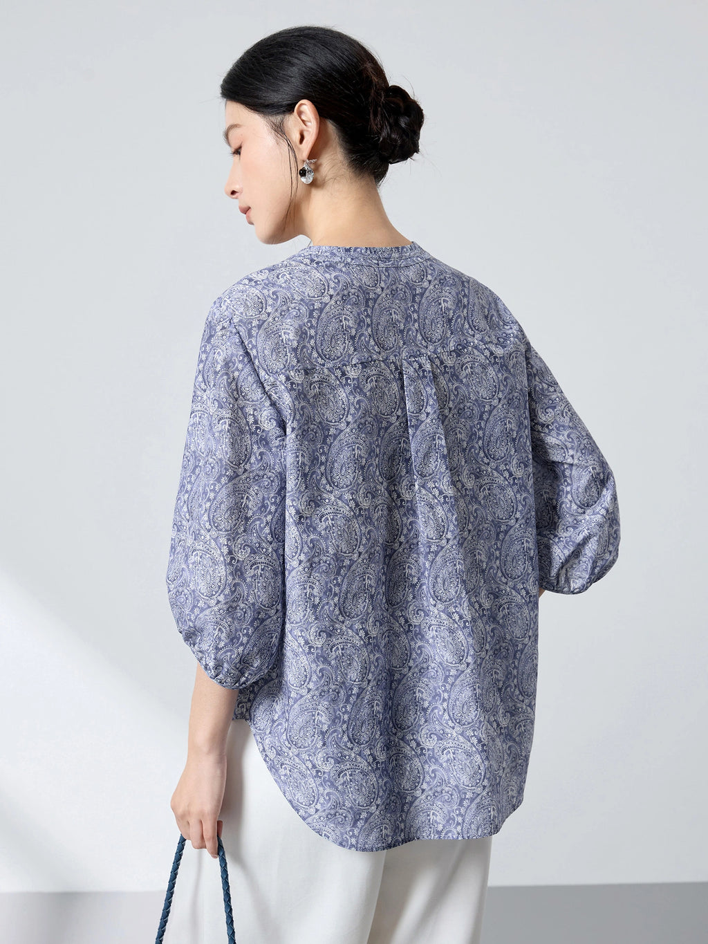 Back view of a blue paisley print cotton-silk blouse with a relaxed fit and lantern sleeves, showcasing the lightweight drape and intricate pattern.