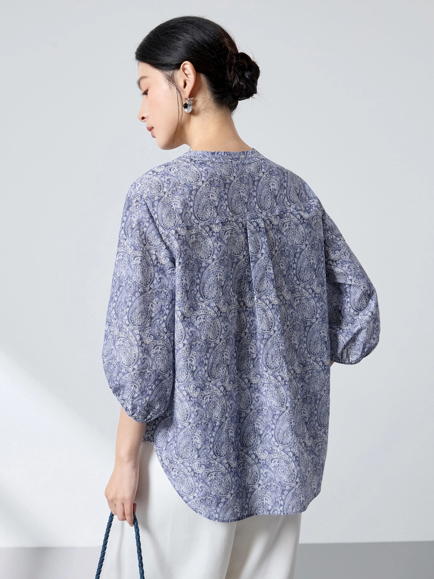 Back view of a blue paisley print cotton-silk blouse with a relaxed fit and lantern sleeves, showcasing the lightweight drape and intricate pattern.