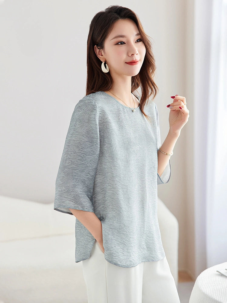 Model wearing a light blue silk-blend New Chinese style top with a round neckline, paired with white trousers.
