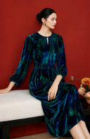 Seated model wearing the blue midi dress with a self-tie belt
