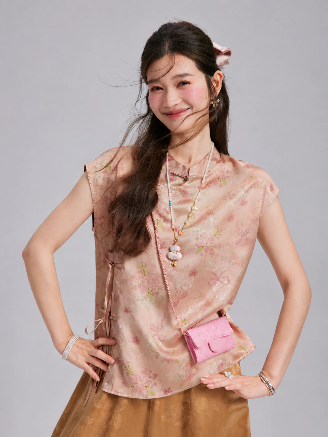 Front styling view of a blush-pink gambiered silk sleeveless top with delicate flowers and butterfly motifs