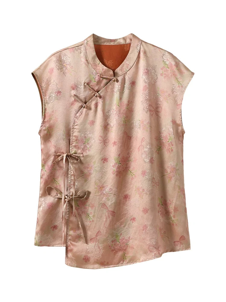 Front product view of a blush-pink Xiangyunsha silk sleeveless top with floral print, asymmetric closures and side bow ties