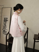Back view of a blush pink 100% mulberry silk vest featuring subtle butterfly-inspired patterns and red piping.