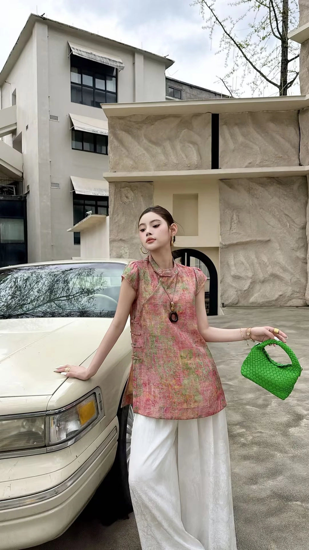 Model wearing a pink New Chinese style top with cap sleeves and subtle floral jacquard, holding a lime green bag, showcasing the vintage-inspired design.
