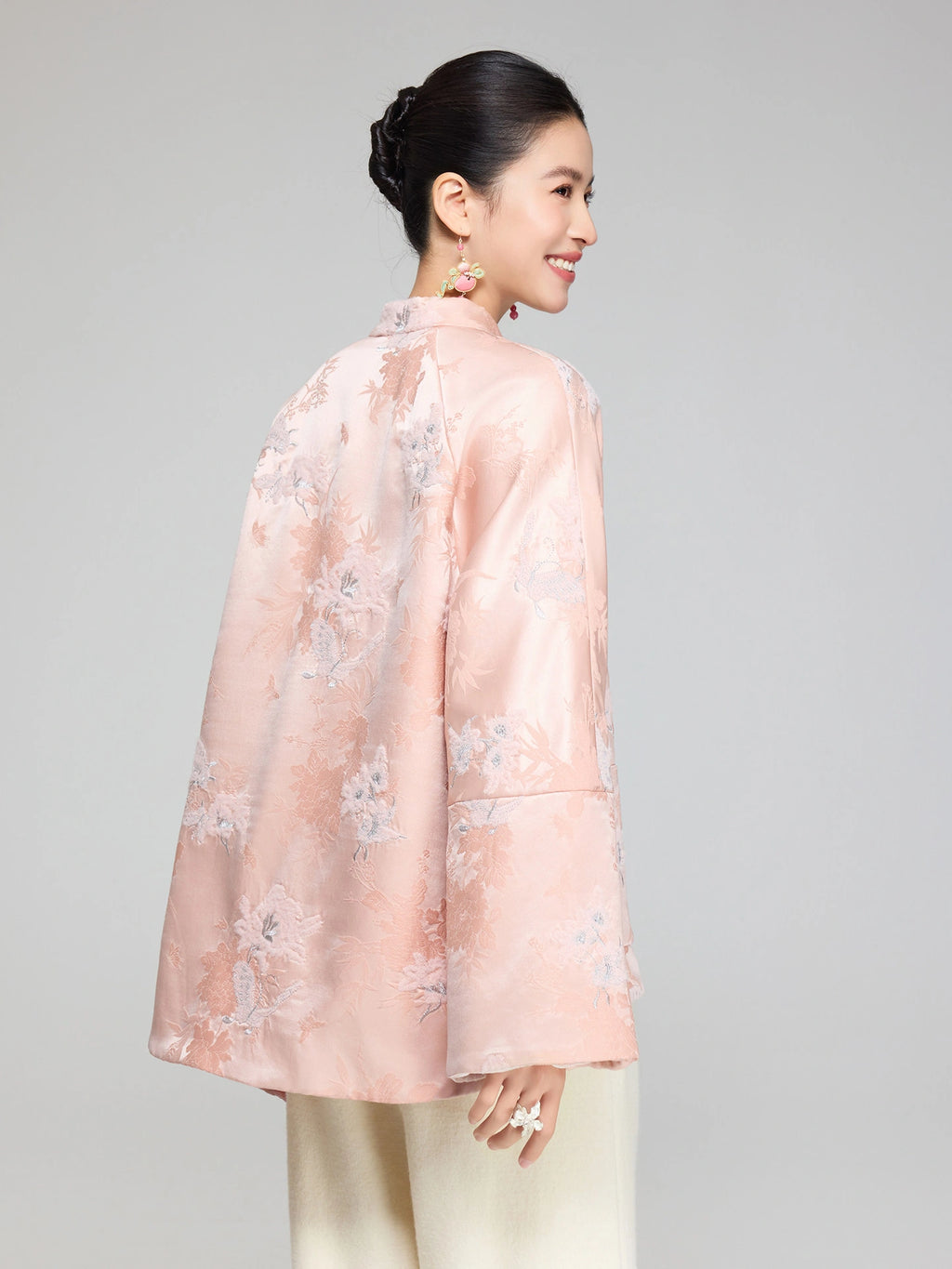 Back view of a blush pink wool and silk padded jacket showing the floral jacquard pattern and longer back hem