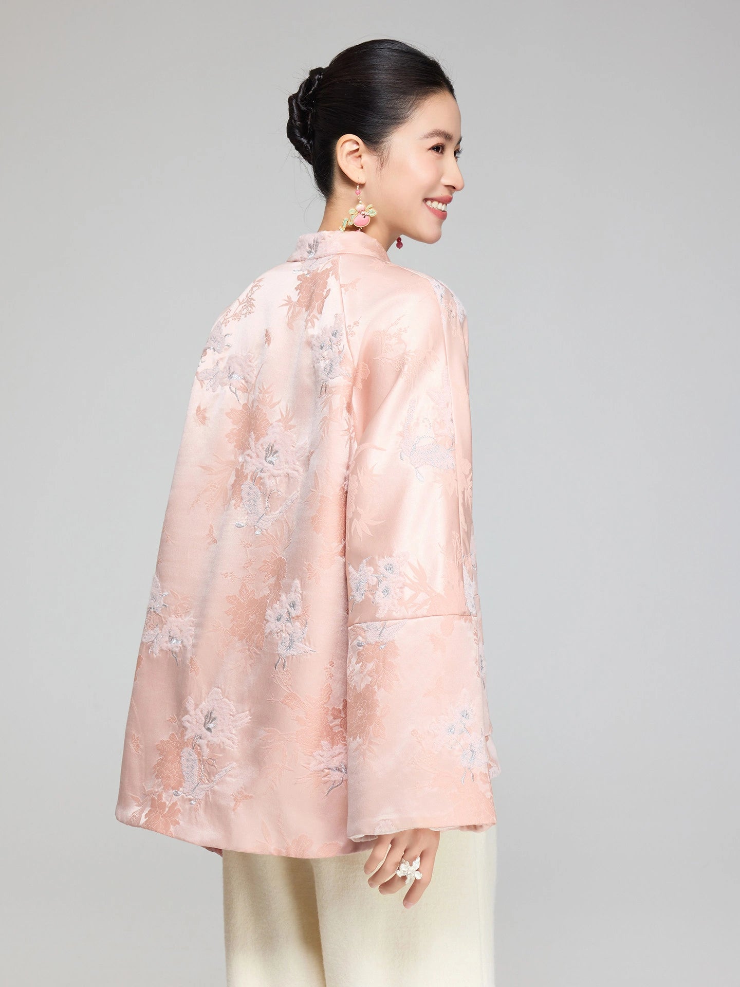 Back view of a blush pink wool and silk padded jacket showing the floral jacquard pattern and longer back hem