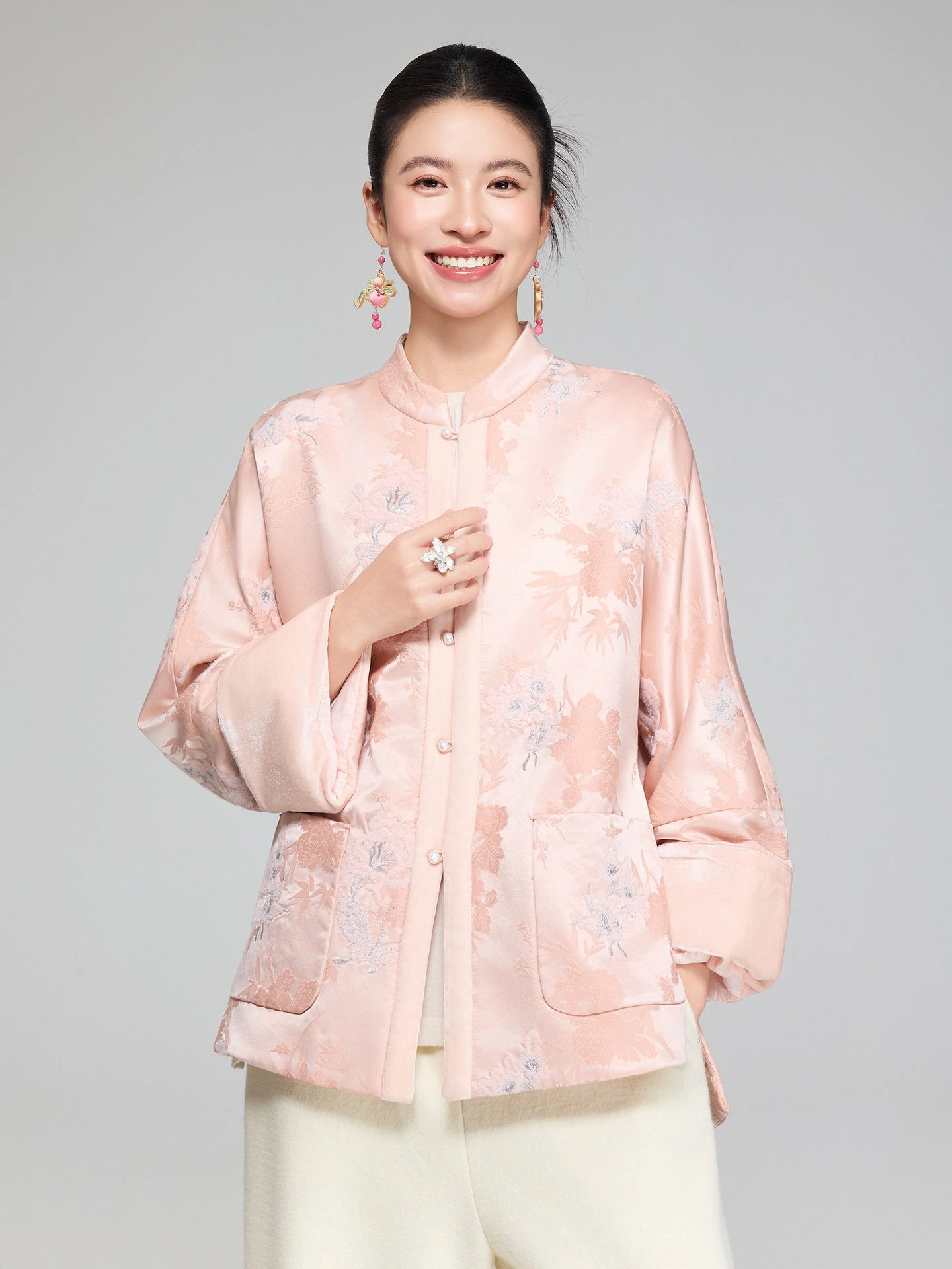 Close-up of the stand collar, pearl-style buttons and floral jacquard texture on the blush pink padded jacket