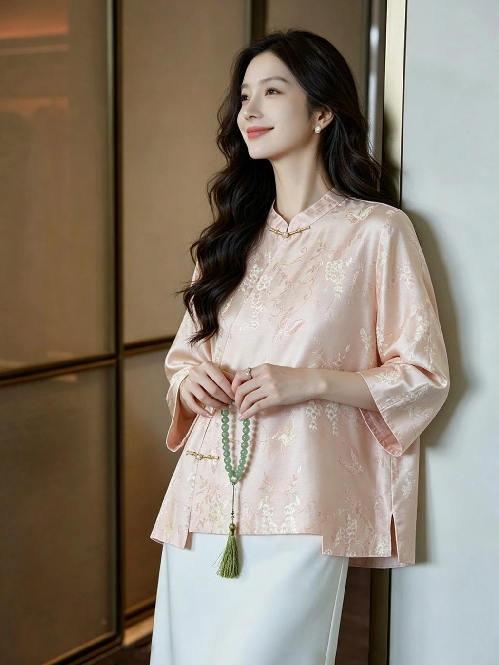Woman wearing a blush pink mulberry silk blouse with three-quarter sleeves and a relaxed silhouette