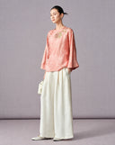 Full-length view of the blush pink sequin embroidered blouse with ivory wide-leg trousers