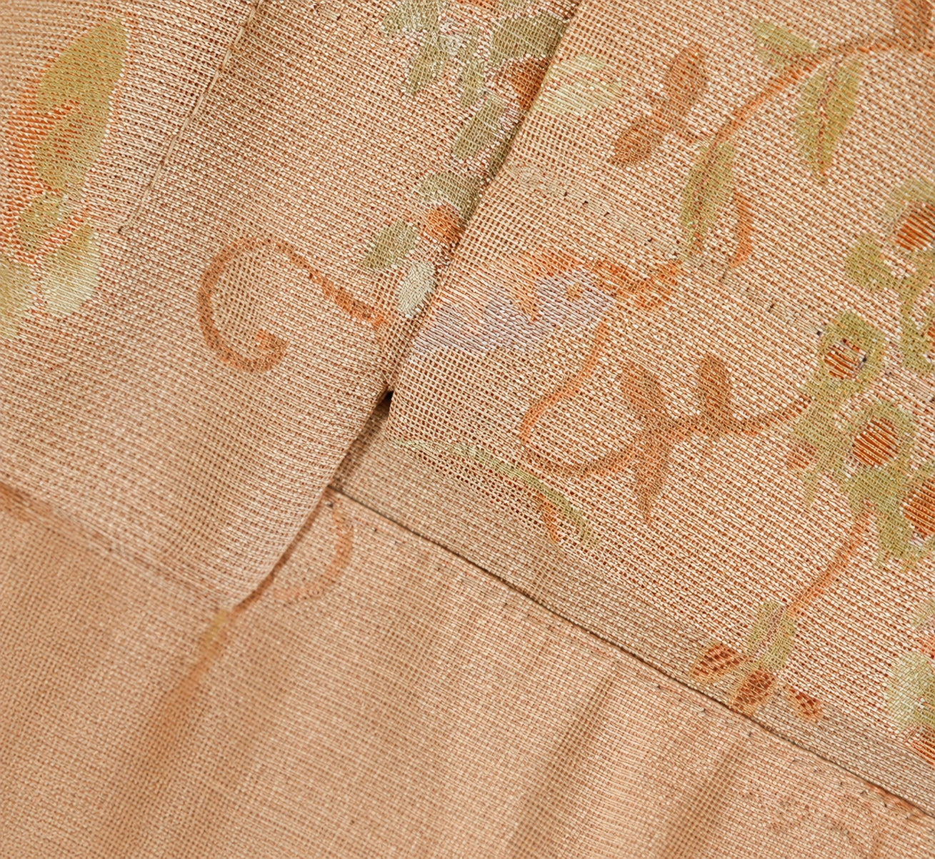 Close-up of the side slit, layered hem and botanical jacquard texture on the pink silk blouse