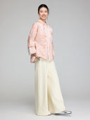 Side view of a blush pink Chinese-inspired padded jacket with wide sleeves and a relaxed straight fit