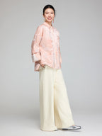 Side view of a blush pink Chinese-inspired padded jacket with wide sleeves and a relaxed straight fit