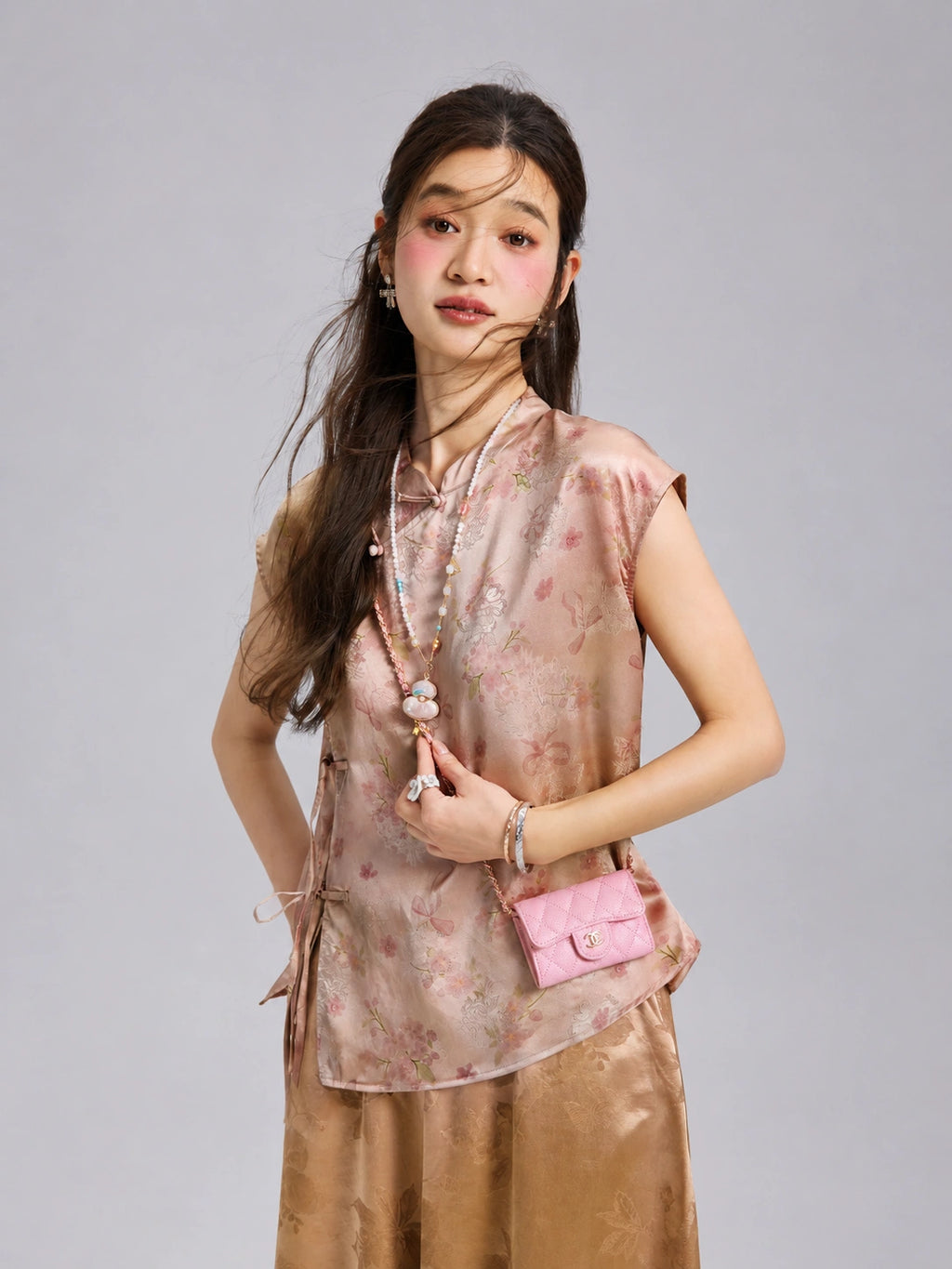 Three-quarter view of a woman wearing a blush floral Xiangyunsha silk top with traditional-inspired closures