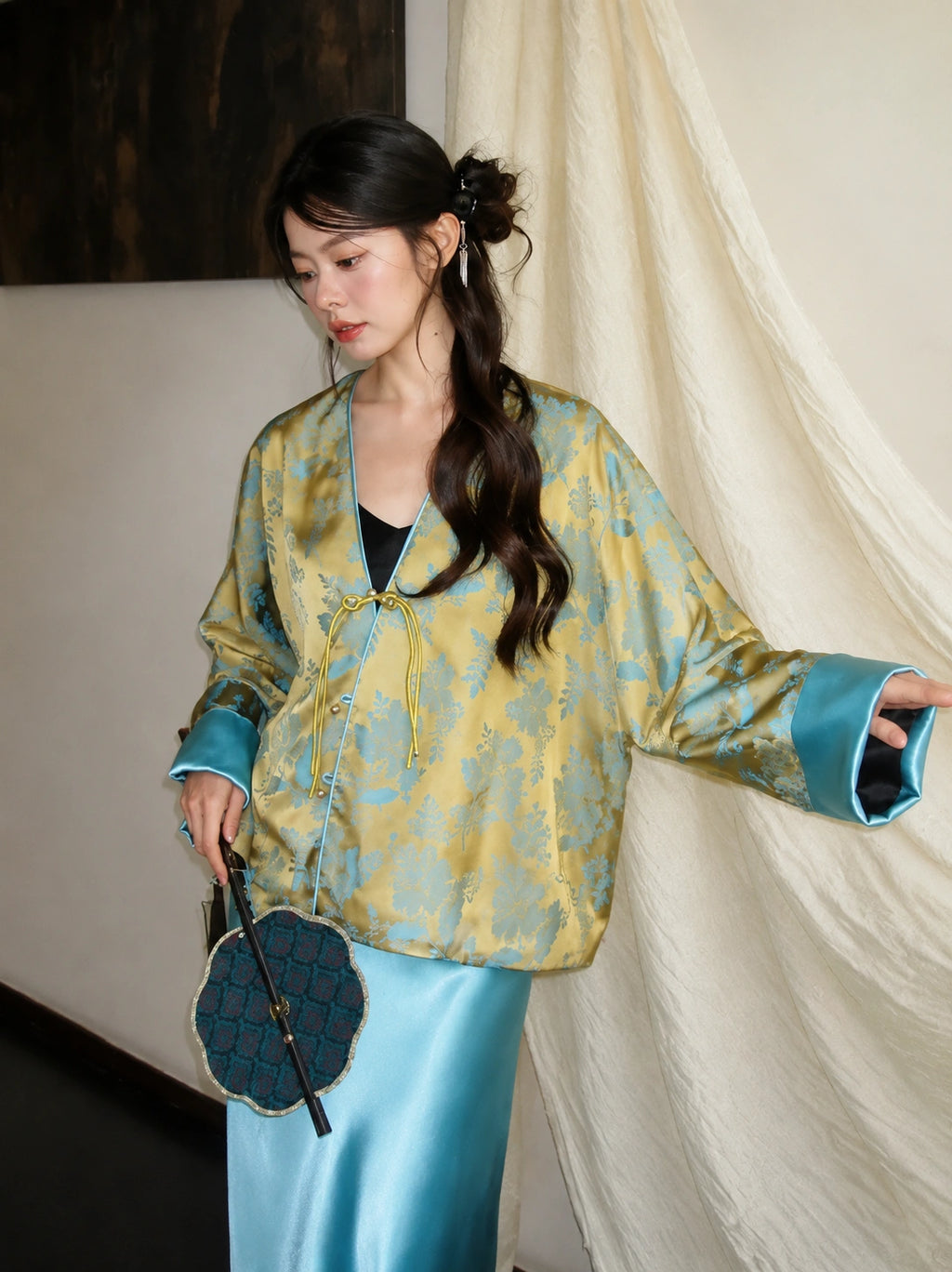 Close-up of a bright blue and gold V-neck jacket with button placket, regular long sleeves, and glossy blue cuffs.