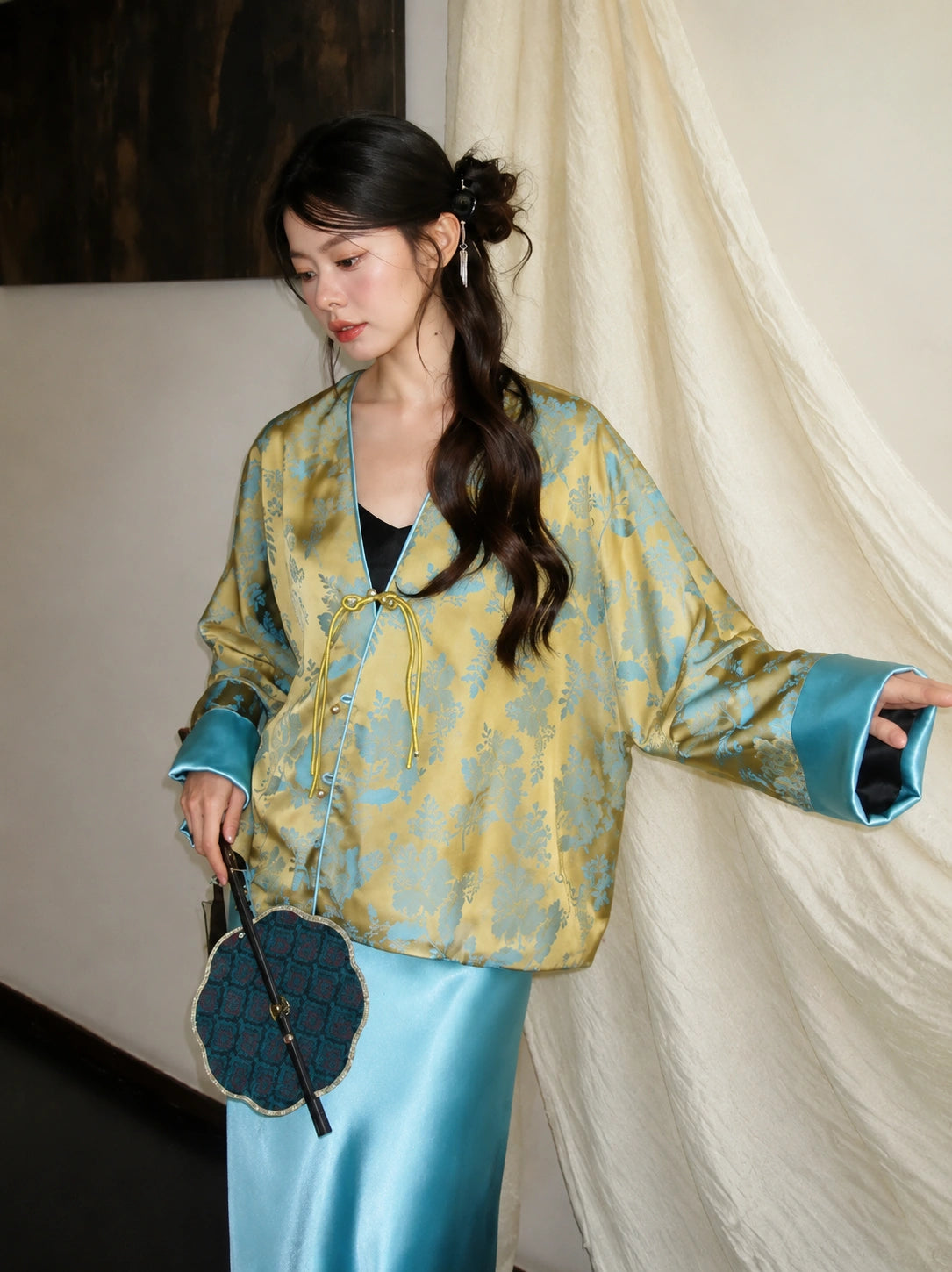 Close-up of a bright blue and gold V-neck jacket with button placket, regular long sleeves, and glossy blue cuffs.