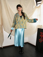 Full-body look featuring a bright blue and gold V-neck triacetate jacket with button front, styled with a glossy acetate water-blue skirt.