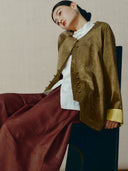 Model wearing a bronze silk-blend jacket with a round neckline, Chinese-inspired buttons and subtle bamboo motifs.