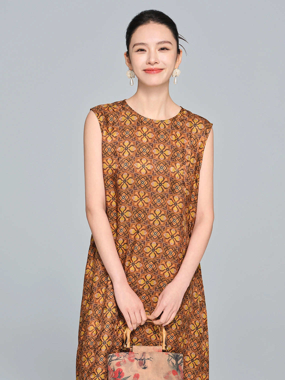 Front close-up of a brown silk dress featuring a round neckline, relaxed silhouette, and ornate yellow geometric print.