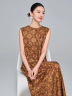 Seated model in a brown silk A-line dress with a round neckline and yellow/gold geometric pattern, showcasing the relaxed and elegant fit.