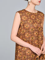 Side profile of a women's brown silk dress showing the sleeveless design, round neckline, and intricate batik-style print.