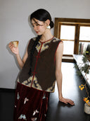 Close styling view of a brown mulberry silk vest with burgundy trim and ornate gold woven accents.