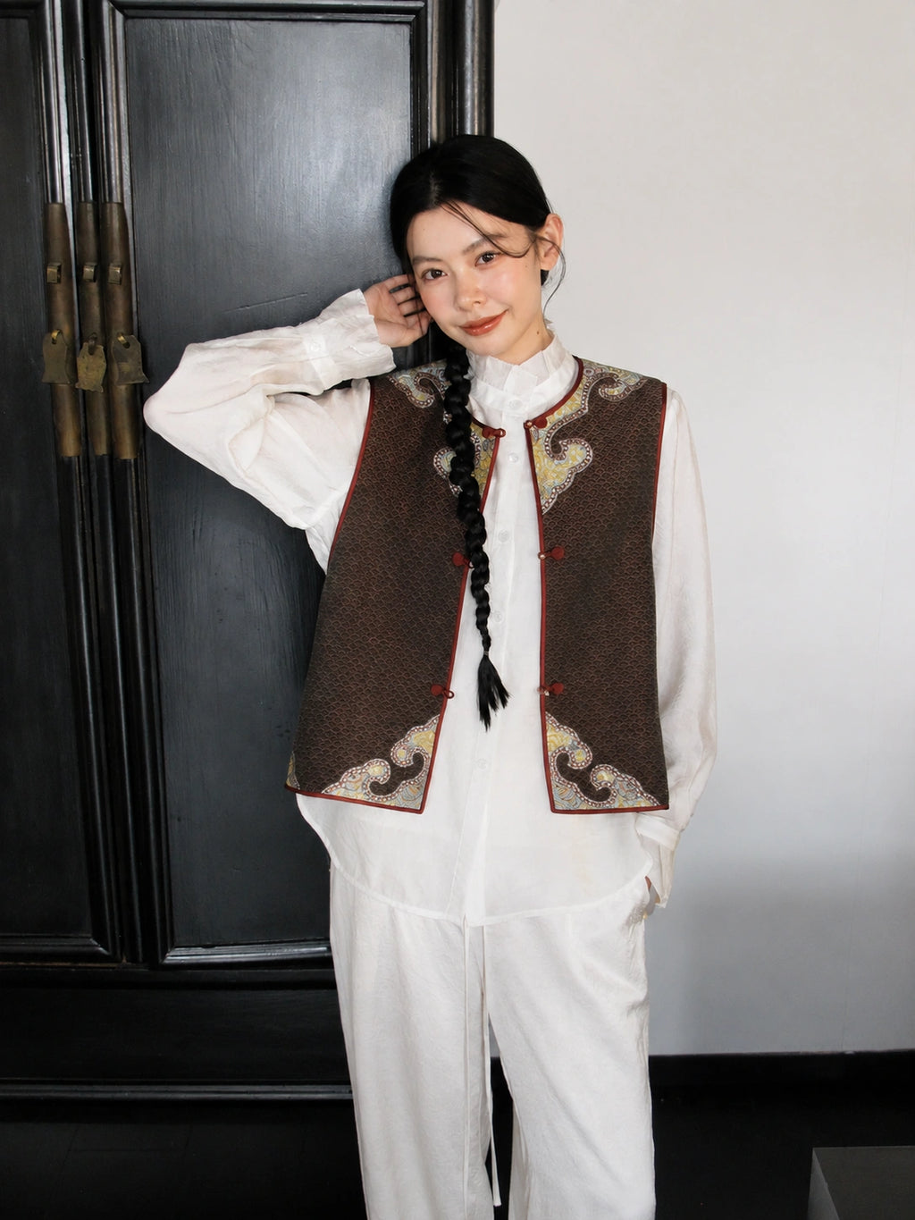 Front view of a brown Songjin silk vest featuring a round neckline, traditional frog closures, and decorative gold panels.