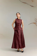 Front view of a women's burgundy sleeveless Cheongsam-inspired top with button-down front, paired with a matching maxi skirt with curved seam details.