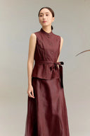 Side view of a burgundy leather-look co-ord set with a tie belt at the waist, showcasing the structured fit and the elegant drape of the 100% silk fabric.