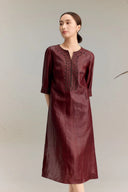 Full body shot of a burgundy silk midi dress with a V-slit neckline and intricate bead embroidery along the chest and cuffs, crafted from 100% mulberry silk, featuring a relaxed A-line silhouette.