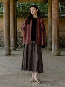 Front view of the collarless Canglan jacket, showing its patterned panels, loose sleeves and dark front edging.