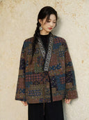 Model looking down while wearing the Cangmo patterned jacket with beaded neckline trim and black trousers.