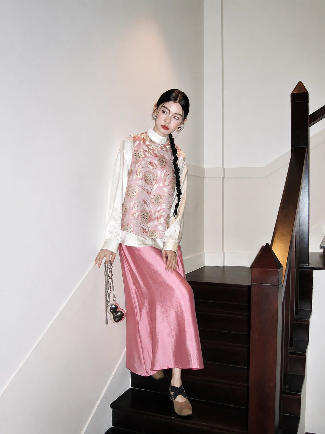 Model wearing the Cardamom and Jade Rabbit pink Song brocade silk vest with a white blouse and pink skirt