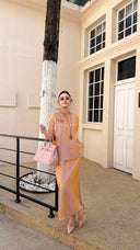 Front view of a women's blush pink Qipao blouse and skirt set, featuring a mandarin collar and relaxed fit, styled with pink handbag and sunglasses.