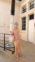 Front view of a women's blush pink Qipao blouse and skirt set, featuring a mandarin collar and relaxed fit, styled with pink handbag and sunglasses.